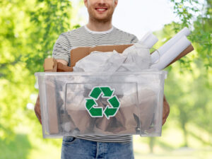 Pulp and paper products lead the way in recycling. Image: Man holding recycling container filled with recyclable paper products.
