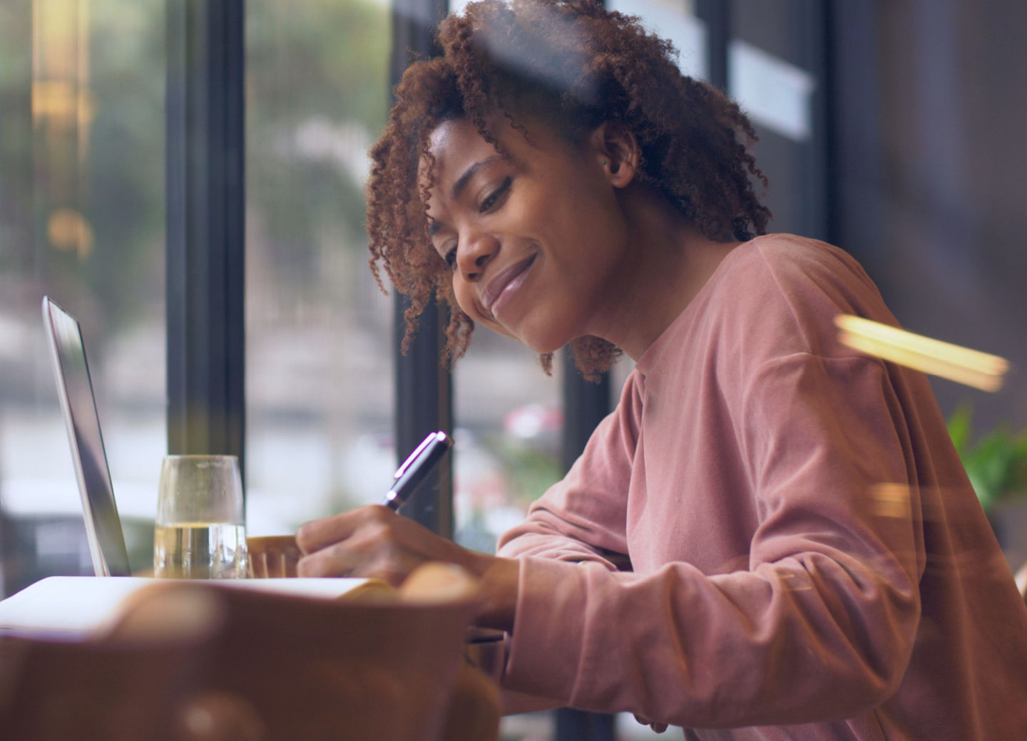 Everyone loves getting a personal letter or note in the mail. If it’s been a while since you wrote a letter, follow these tips at Newsroom.Domtar.com. Image: Black woman in pink shirt, writing letter at desk in front of computer.