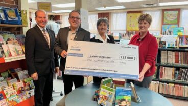 Image: Two men and two women are smiling while holding a donation check from Domtar in the amount of $225,000 to support the construction of a new local library in Windsor, Quebec. They are standing in the children’s literature area of the library. Domtar’s commitment to literacy drives our investments in community libraries like this one.