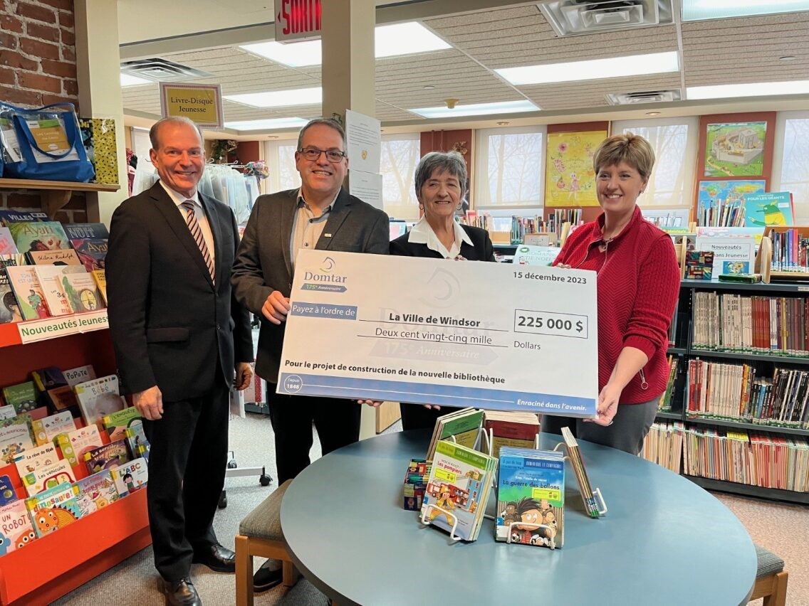 Image: Two men and two women are smiling while holding a donation check from Domtar in the amount of $225,000 to support the construction of a new local library in Windsor, Quebec. They are standing in the children’s literature area of the library. Domtar’s commitment to literacy drives our investments in community libraries like this one.