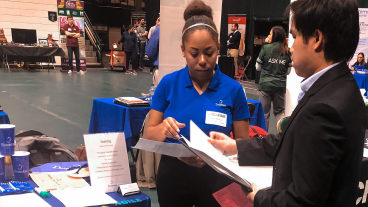 Talia Massey talks with a student at a college career fair in 2018. (Photo taken prior to COVID-19 pandemic.)