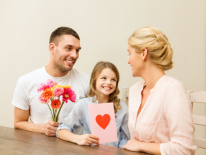 Valentine's Day - Couple with child at table with flowers and card.