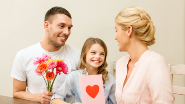 Valentine's Day - Couple with child at table with flowers and card.