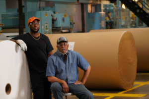 United Steelworkers union members next to rolls of paper