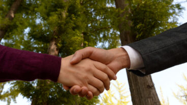 Sustainability partners enrich Domtar's sustainability journey. Photo of handshake with backdrop of trees.