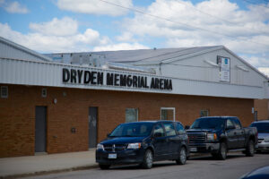Photo of exterior of Dryden Memorial Arena with cars parked in front.