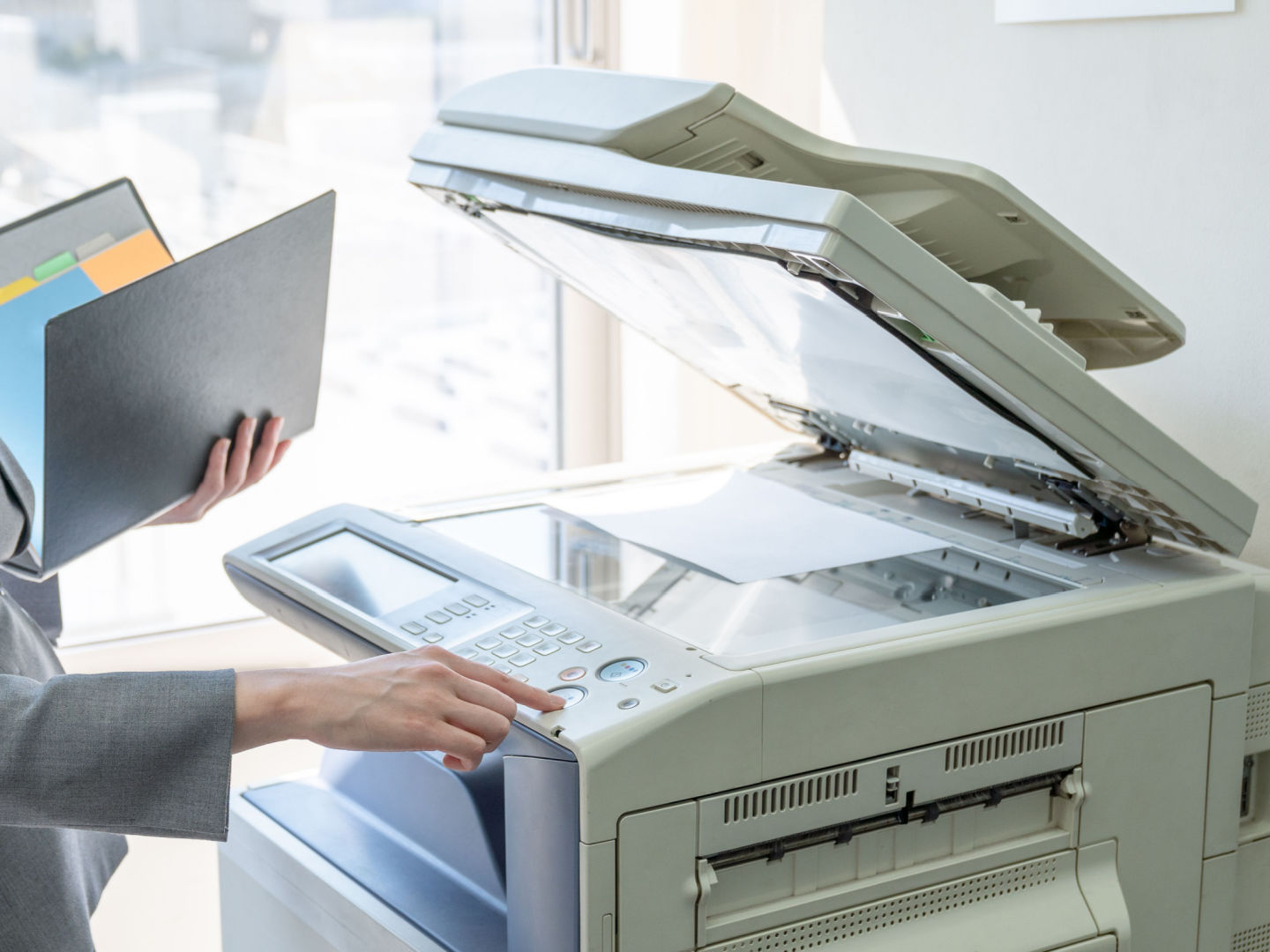 A business person standing next to copy machine with paper on the scanner and binder in their left hand. The person is typing in how many copies they need. Which industries use the most paper? We’ve rounded up the top five to explore why some industries prefer print.