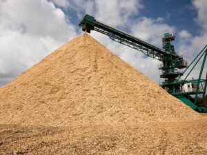 Photo of wood chips in Plymouth Mill woodyard, with chips exiting the chipper machine. Lean Six Sigma and continuous improvement measures drive benefits for Domtar.